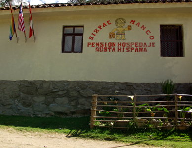 Image of the outside of Sixpac Manco Hospedaje showing Vincent R. Lee's 'Sixpac Manco Publications' Logo painted onto the wall and the flags of Cuzco, the USA and Peru