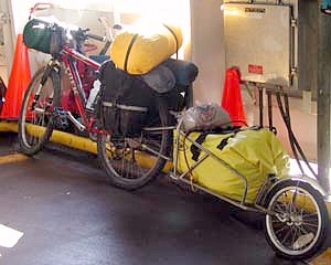 Photograph of the fully loaded bike with trailer behind leaning against a wall.