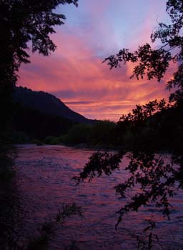 Sunrise along the Manso, the sky is red and orange between the walls of the Rio Manso valley.